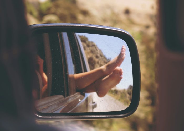 Illustration de la Prestation Forfait Relax de la Conciergerie Émilie Coudenneau à Bordeaux, avec un rétroviseur montrant des pieds détendus à l’extérieur d’une voiture.
